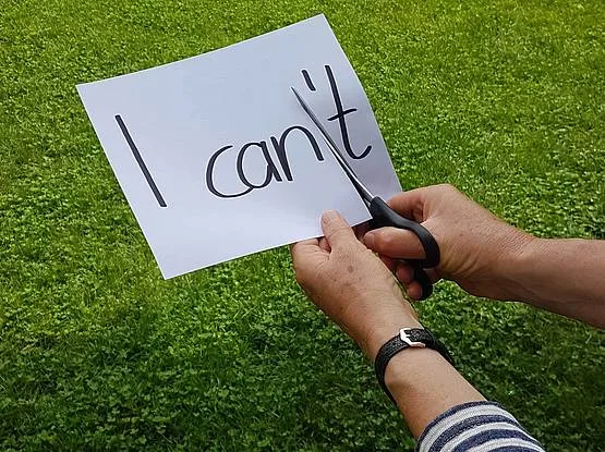 Eine Schere schneidet das t aus „I can’t“